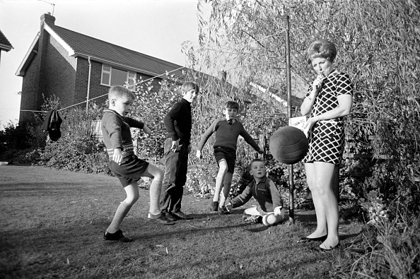 Bobbie Leigh coaching the boys of Ashton Junior Football Club in her garden, 1968. While awaiting access to nearby farmland for training and matches, the team used Bobbie’s garden as their temporary training ground. Four boys are pictured alongside Bobbie, who holds a whistle and an FA rule book.
